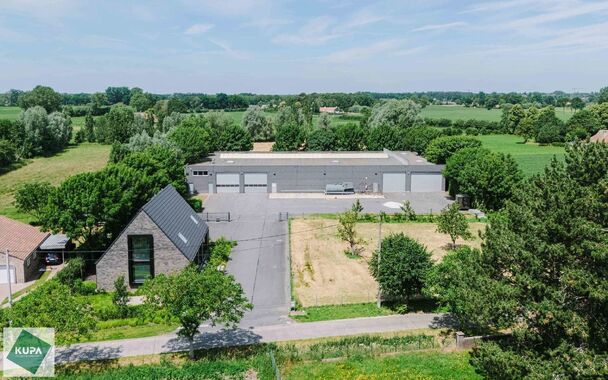 Ruime bedrijfssite met nieuwbouw kantoorgebouw, achterliggende loods van circa 1.680 m&sup2; en aansluitend weiland.
Vooraan aan de straat bevindt zich een recent en luxueus kantoorgebouw met ca. 160 m&sup2; bebouwde oppervlakte, bestaande uit gelijkvloers, eerst
