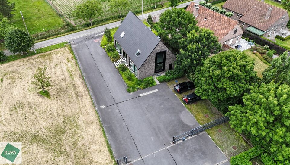 Ruime bedrijfssite met nieuwbouw kantoorgebouw, achterliggende loods van circa 1.680 m&sup2; en aansluitend weiland.
Vooraan aan de straat bevindt zich een recent en luxueus kantoorgebouw met ca. 160 m&sup2; bebouwde oppervlakte, bestaande uit gelijkvloers, eerst