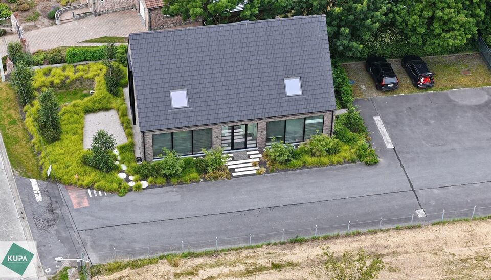 Ruime bedrijfssite met nieuwbouw kantoorgebouw, achterliggende loods van circa 1.680 m&sup2; en aansluitend weiland.
Vooraan aan de straat bevindt zich een recent en luxueus kantoorgebouw met ca. 160 m&sup2; bebouwde oppervlakte, bestaande uit gelijkvloers, eerst